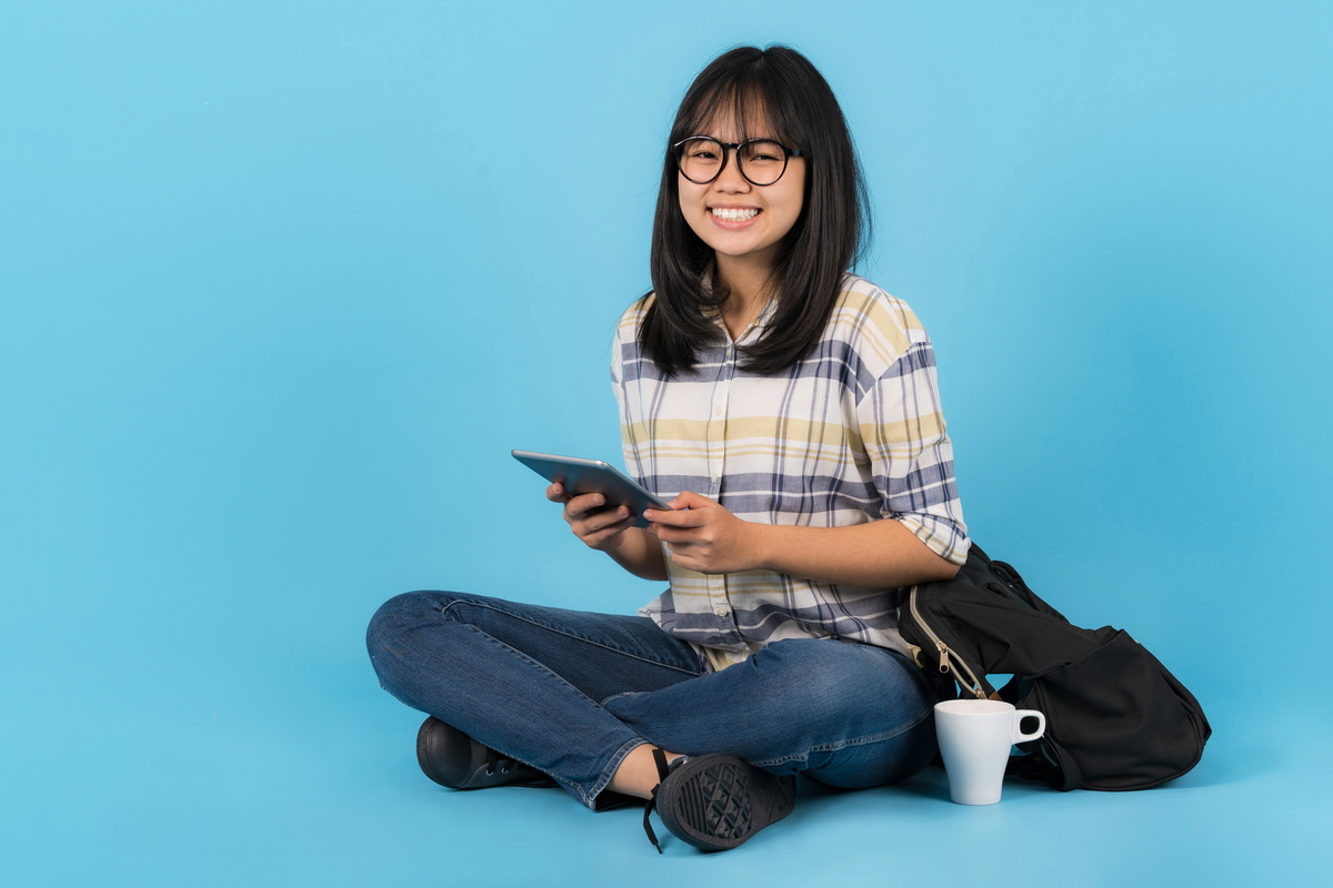 Happy Asian Student Sitting with Using Tablet